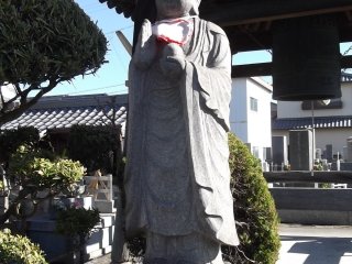 Pho tượng một người sùng đạo canh gác chuông chùa