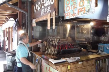 <p>Fish grilling on their sticks at one of the food stands</p>