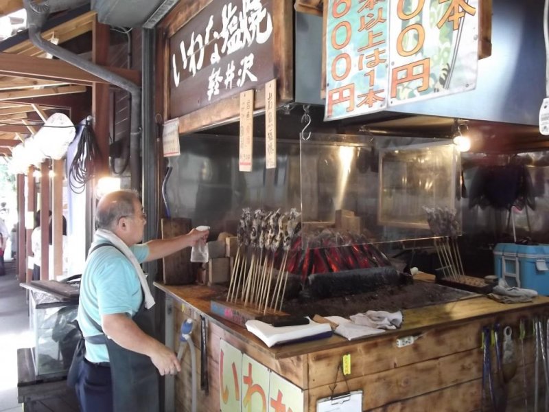 <p>Fish grilling on their sticks at one of the food stands</p>