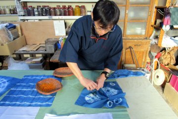 The manager shows us how to create different patterns in the indigo dye