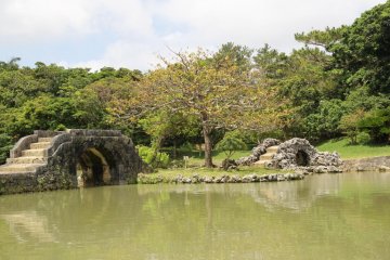 <p>Two stone archway bridges lead to small island in the center of the pond at Shikanaen Royal Garden</p>