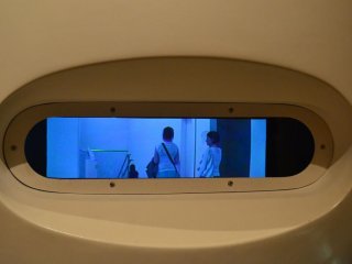 The camera inside this exhibit records the movements of passers by at high speed. This thin and wide blue LCD is able to replay the recorded movements several times over in many styles.