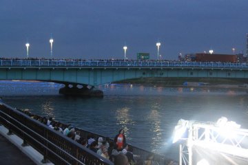 There was a huge crowd on the bridge as well. Just beyond the bridge, the LED lights, called inori boshi (prayer stars in Japanese), are starting to float down the river.