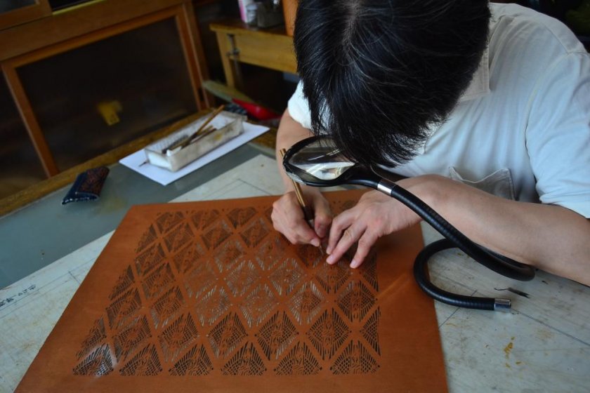 Mr. Ono, the shop manager, demonstrates the delicate process of stencil cutting. 