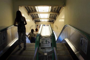 Passengers stand to the left of the left escalator