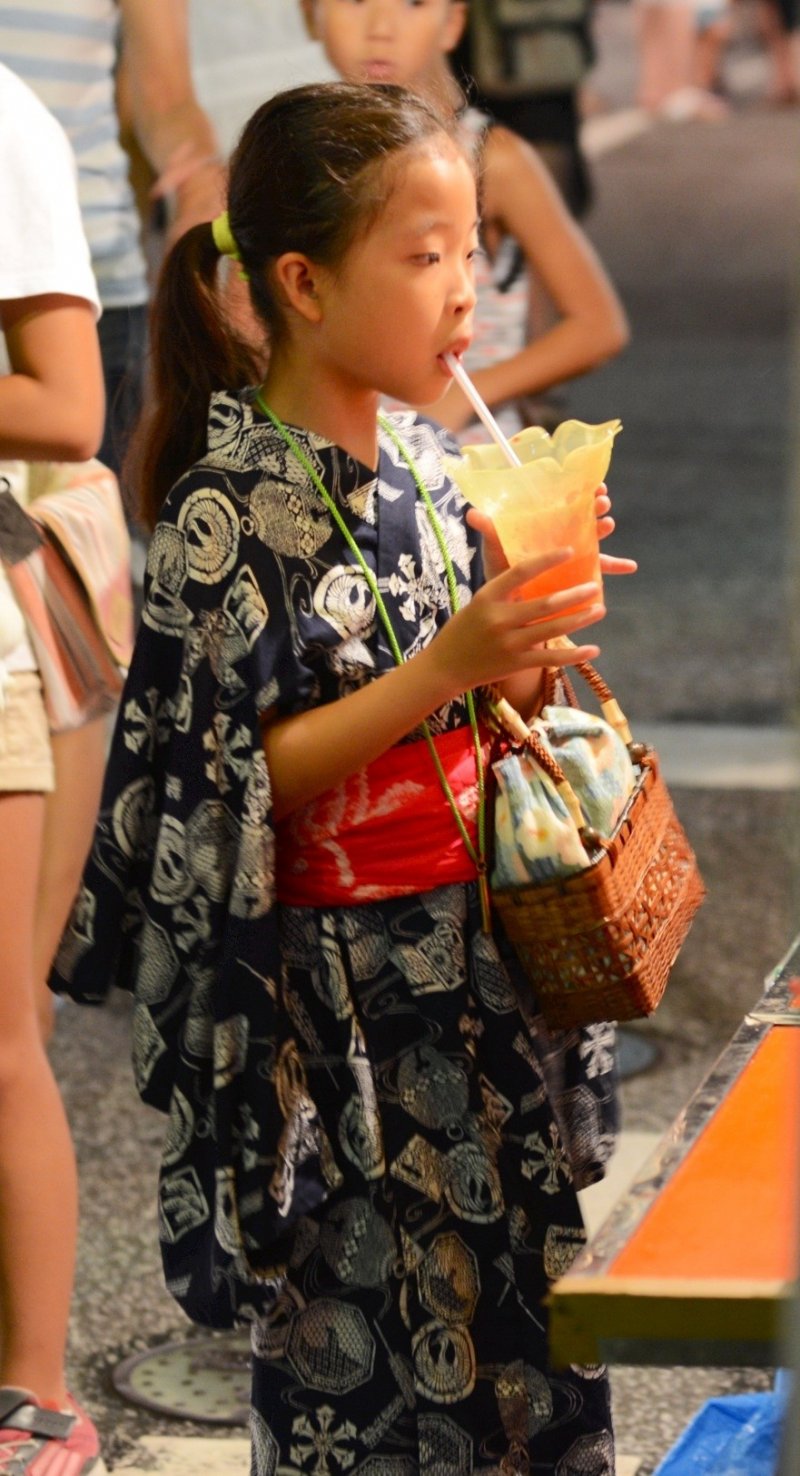 A young girl wearing a Kimono and drinking an ice slush