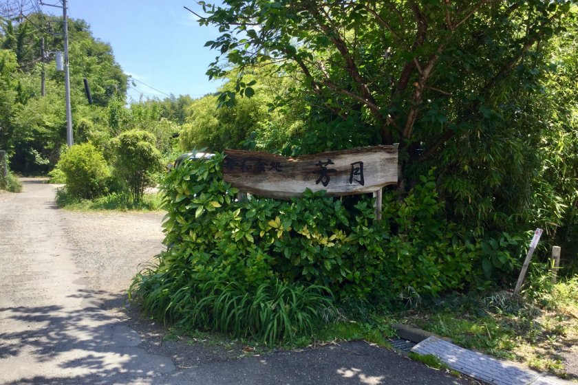 Sign at the end of the road. The restaurant is hidden behind the bushes.