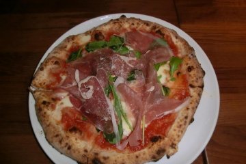 Margarita pizza with raw ham and herb leaf