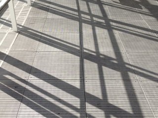 Overhead walkway Shibuya station: Footsteps crossing diagonal shadows