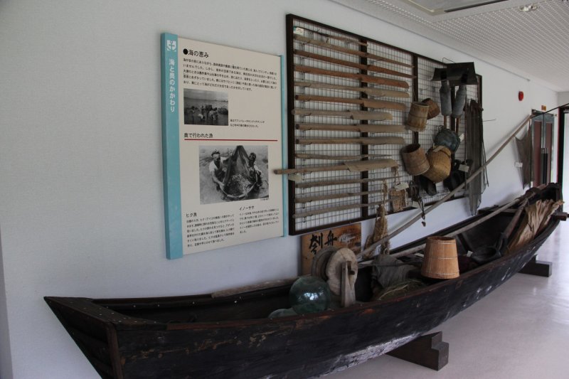 <p>A traditional sabani on display in the passage way just outside of the main exhibit hall is shown with many of the tools used by uminchu - the Uchina Guchi (Okinawan language) word for fishermen or&nbsp;people of the sea</p>