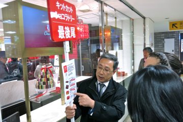 <p>A KitKat Chocolatory&nbsp;staff member holds a sign indicating the end of line and flavors available.</p>