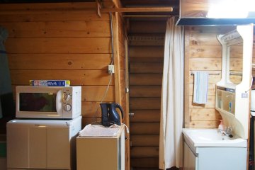 <p>อีกมุมหนึ่งภายในบ้านพัก ทางซ้านเป็นตู้เย็น ไมโครเวฟ กระติกน้ำร้อน และสุดทางเดิน ซ้ายมือเป็นห้องอาบน้ำ และขวามือเป็นห้องสุขา</p>
